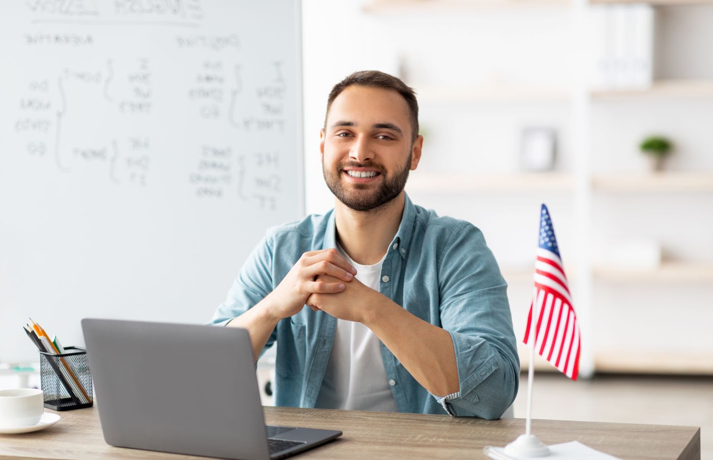 An educational consultant giving an online consultation from his desk with a small U.S. flag